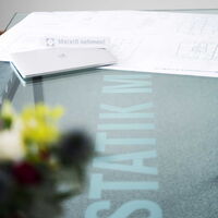 Laptop auf Glastisch, der mit dem Firmenlogo gekennzeichnet ist.