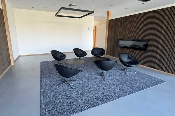 Moderner Besprechungsaum mit Sesseln und kleinen Tischen.