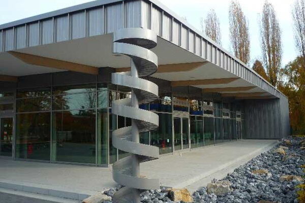 Frontalansicht des Eingangs der Mesa unter dem Vordach. Im Forderung steht eine spiralförmige Statue.