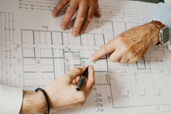 3 Hände auf einem Bauplan Zeigen und notieren.