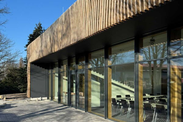 Aussenfassade aus Holz mit Blick auf eine große Fensterfront.