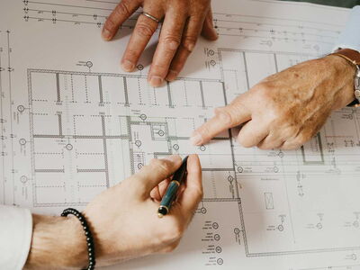 3 Hände auf einem Bauplan Zeigen und notieren.