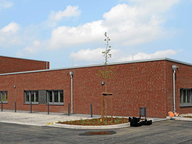 Aussenansicht eines rostrot verklickerten Gebäudes für einen Schießstand.