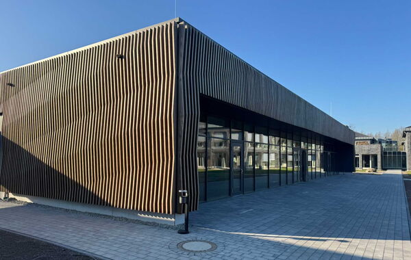 Aussenfassade eines Schulungszentrums mit großer Glasfassade und gepflastertem Vorplatz.