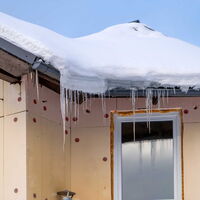 Haus mit Wärmedämmung unverputzt zu sehen. Auf dem Dach liegt Schnee und Eiszapfen sind zu sehen.