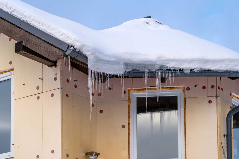 Haus mit Wärmedämmung unverputzt zu sehen. Auf dem Dach liegt Schnee und Eiszapfen sind zu sehen.