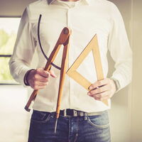 Foto eines Menschen welcher Zirkel und Geodreieck in den Händen hält.
